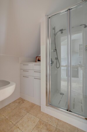 A modern bathroom with a glass-enclosed shower, a white sink, and a cabinet with drawers.