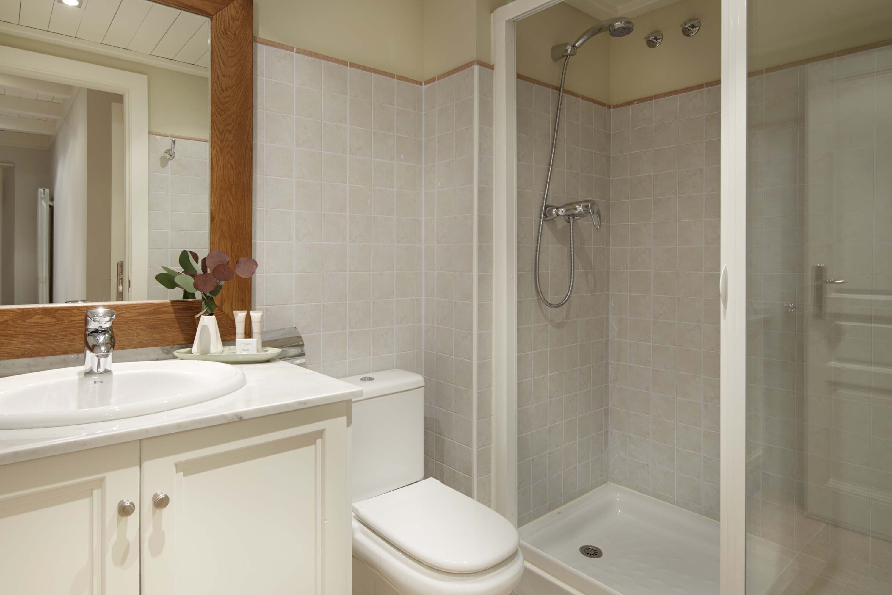 Un baño con lavamanos, inodoro y zona de ducha.