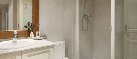 Un baño con lavamanos, inodoro y zona de ducha.