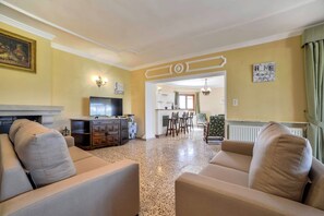 A living room with a television, sofa, and a dining area with chairs and a table. - Villa Puchero - PlusHolidays (Calpe)