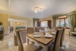 A dining area with a table set for four, chairs, a sofa, and a pool table in the background.