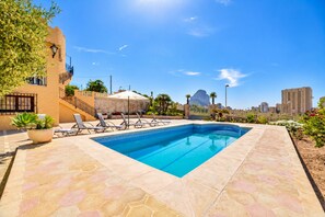 Piscina com espreguiçadeiras e um vaso de planta.