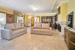 Uma sala de estar com dois sofás, lareira e área de jantar com um armário.