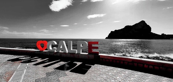 A coastal view with a sign reading "OGALPE" and a mountain in the background.