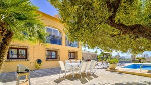 A patio area with outdoor seating, a pool, and a building with balconies. - Villa Puchero - PlusHolidays (Calpe)