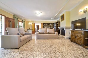 Uma sala de estar ampla com dois sofás, lareira e televisão.