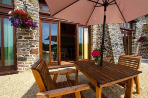 A wooden table and chairs set outdoors with a stone building in the background.