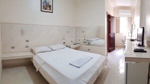A hotel room with a large bed, a desk with a computer, a TV, and a refrigerator. - Hotel Premier (Campo Grande)