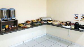 A breakfast buffet setup with various food items and beverages. - Hotel Premier (Campo Grande)