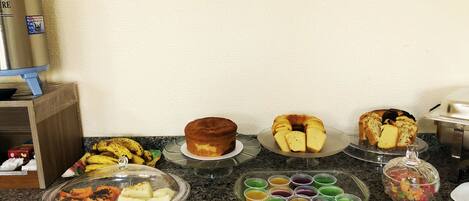 A breakfast buffet with various pastries, cakes, and fruit cups.