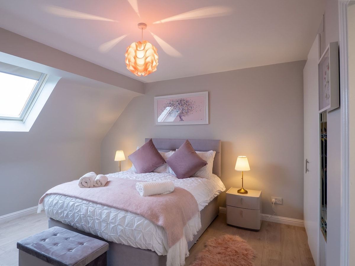 Un dormitorio con cama, mesitas de noche, una ventana y una lámpara en el techo.