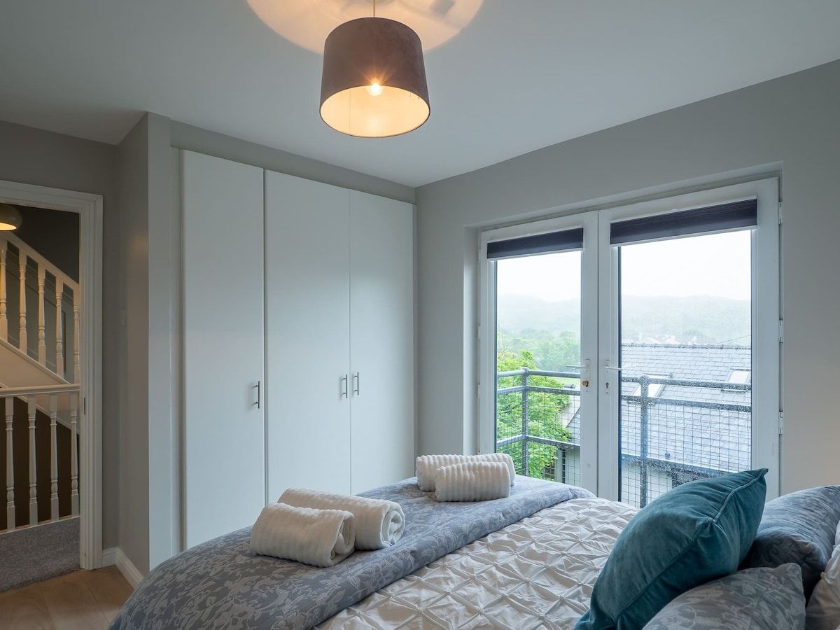 Un dormitorio con cama, armario y balcón con vistas.