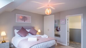 Ein Schlafzimmer mit Bett, Nachttischlampen, Deckenventilator und einem großen Spiegel.