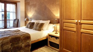 Une chambre à coucher avec un grand lit, une tête de lit en bois, des lampes de chevet et une armoire.