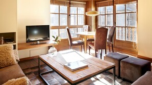 Un salon chaleureux avec une table basse en bois, des sièges confortables, un téléviseur et de grandes fenêtres offrant une belle vue.