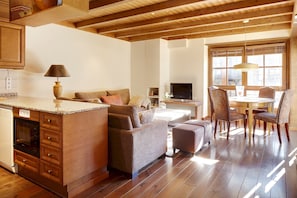 A modern kitchen with wooden cabinets, a built-in oven, and a dining area with a round table and chairs.