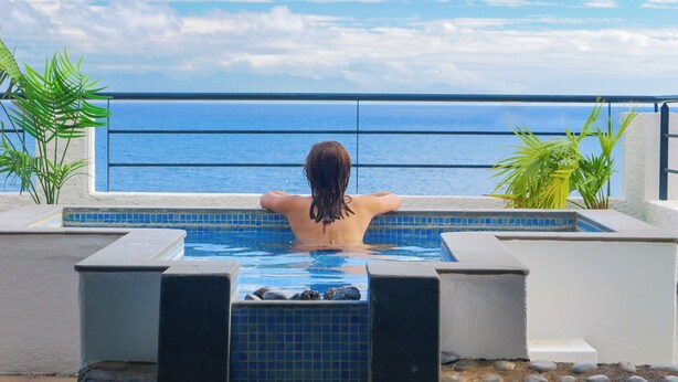 Una persona relajándose en un jacuzzi con vista al océano.