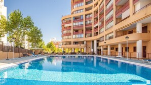 A swimming pool with lounge chairs and a building with multiple balconies in the background. - Nautilus 39B - Grupo Turis - Calpe, Costa Blanca (Calpe)