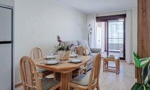 Un comedor con una mesa de madera dispuesta para cuatro personas, rodeado de sillas de mimbre.