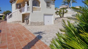 Une maison à deux étages avec une façade en pierre, un hall d’entrée carrelé et un petit balcon.