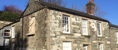 A stone building with multiple windows and a chimney.