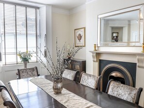 A dining room with a long table, chairs, a vase with branches, a fireplace, and a large mirror. - Tavistock Town House (Tavistock)
