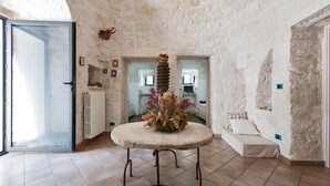 A stone-walled room with a round table, a radiator, and a bed with a pillow. - Villa Ricci by Perle di Puglia (Ceglie Messapica)