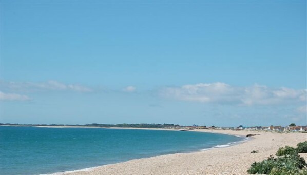 A beach with pebbles and a clear blue sky.