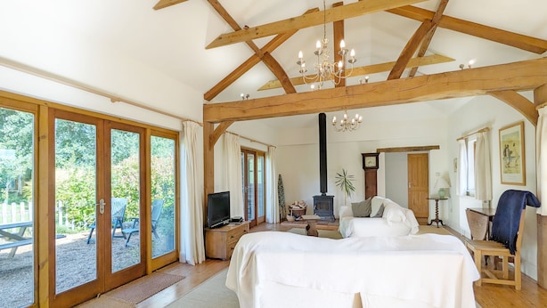 Um quarto espaçoso com uma cama grande, vigas de madeira, um candelabro, televisão e vista para o exterior.
