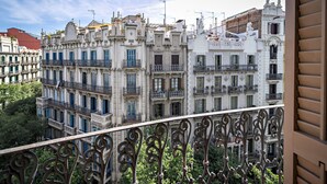 Un edificio de varios pisos con balcones ornamentales y barandilla de hierro forjado.