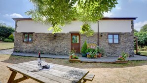 A stone house with a wooden table and potted plants in the yard. - 3 Bed in Barnstaple (oc-n1991) (Bratton Fleming)
