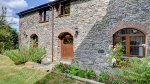 A stone building with two arched windows and a wooden door. - 3 Bed in Barnstaple (oc-n1991) (Bratton Fleming)