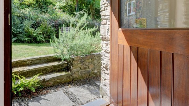 An arched doorway leading to a garden with stone steps and a wooden door. - 3 Bed in Barnstaple (oc-n1991) (Bratton Fleming)