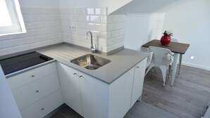 Una cuina moderna amb armaris blancs, una aixeta d'acer inoxidable i una estufa negra.