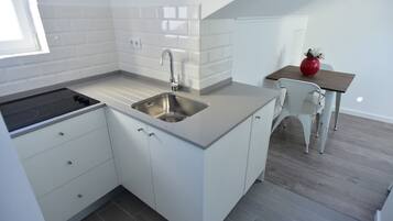 Una cocina moderna con armarios blancos, un lavamanos de acero inoxidable y una estufa negra.