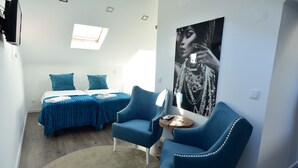 Un dormitori modern amb dos llits, un finestral gran, un armari blau i un cartell a la paret.
