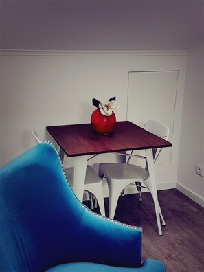 A room with a red vase on a wooden table, white chairs, and a blue armchair.