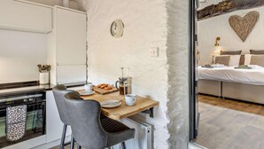 A compact kitchen with a wooden table, chairs, and a coffee maker.