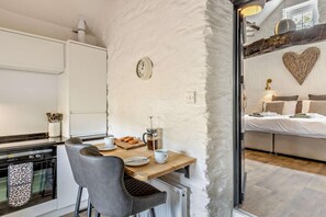 A compact kitchen with a wooden table, chairs, and a coffee maker.