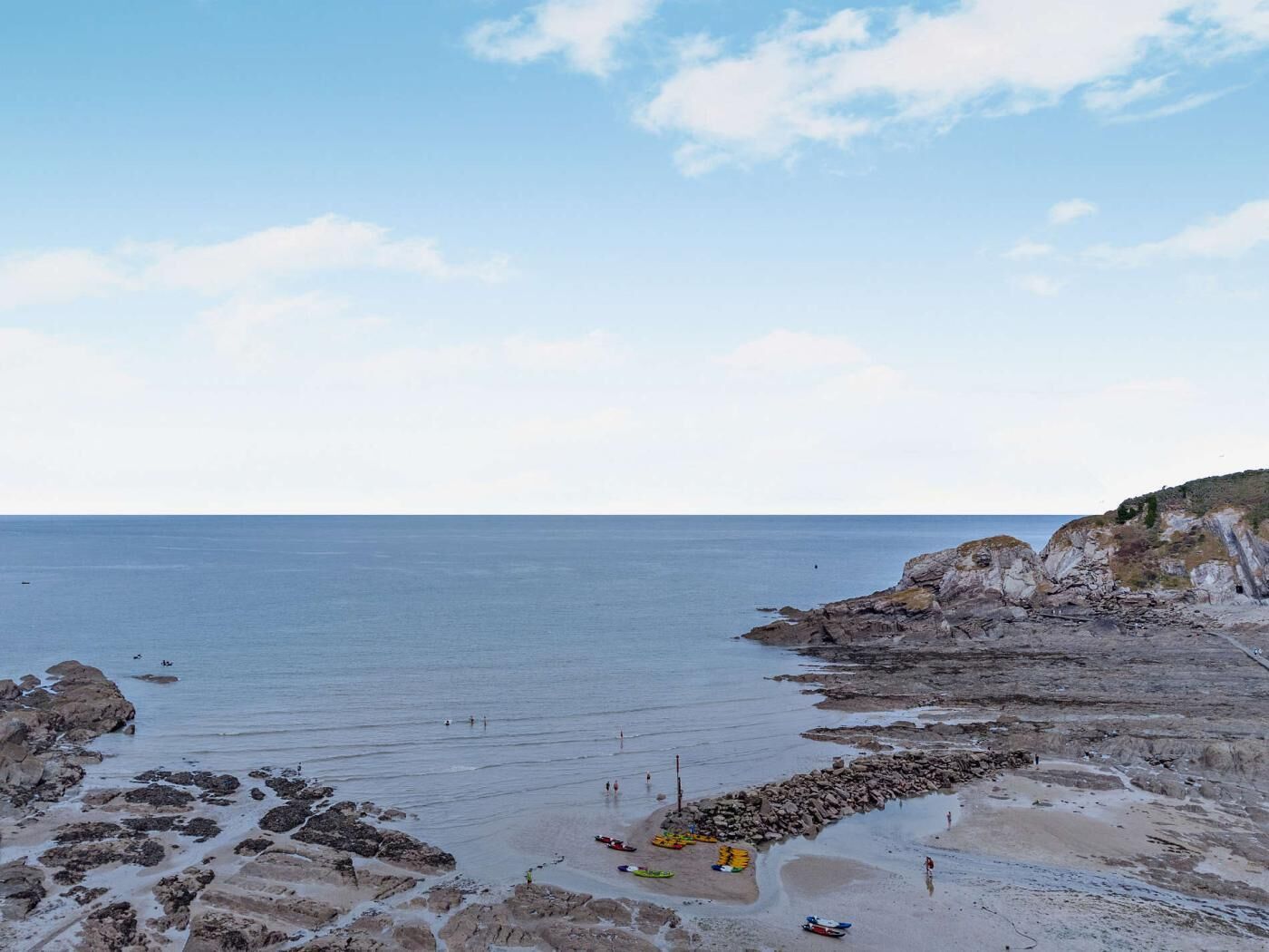 Un paysage côtier caractérisé par un terrain rocheux, un ciel dégagé et une mer calme.