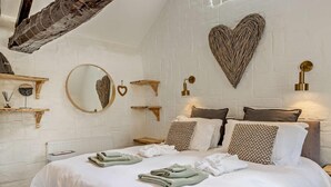 A bedroom with a large bed, wooden headboard, and heart-shaped wall decor.