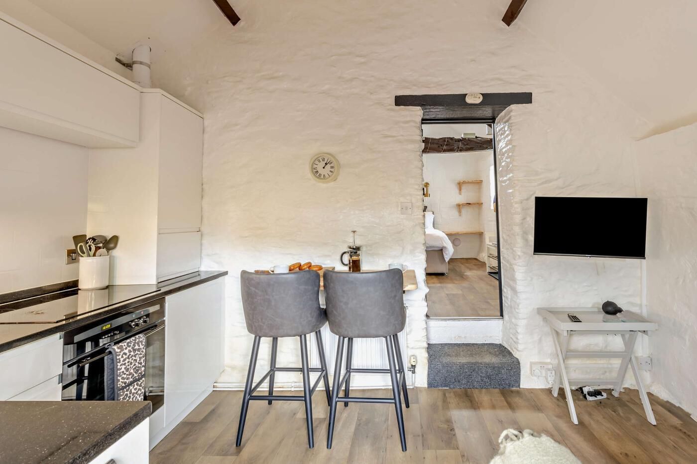 Een moderne keuken met een bar, een klok en een aan de muur bevestigde televisie.