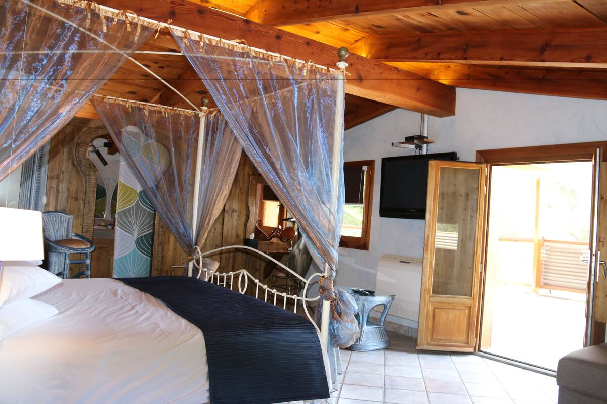 Una habitación con cama, techo de madera, ventana y puerta.