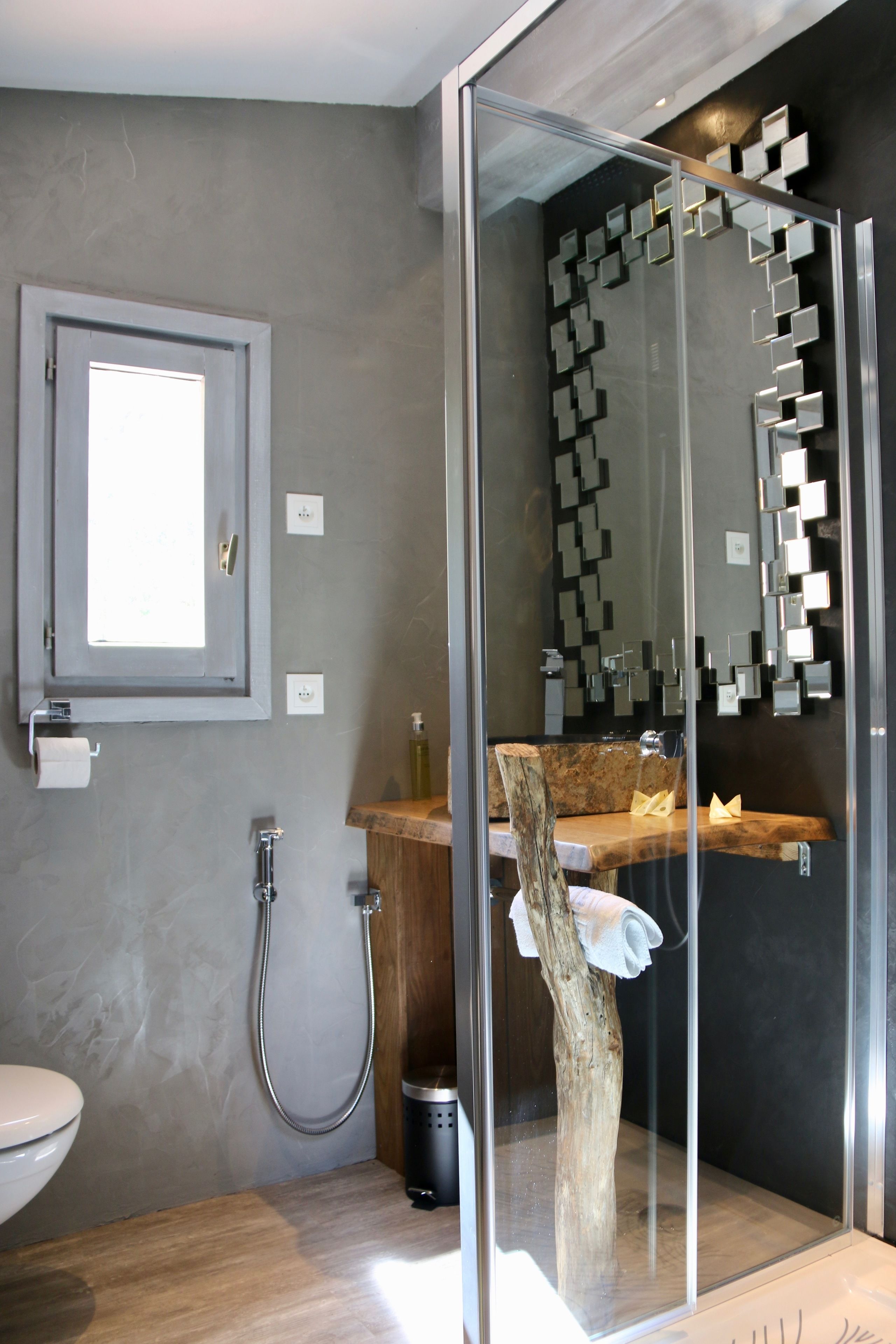 A modern bathroom with a glass shower enclosure, a wooden vanity, and a visible toilet.