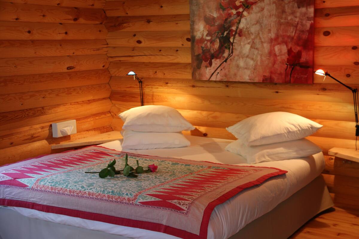 Un dormitorio de estilo cabaña con cama, dos lámparas de noche y un cuadro en la pared.