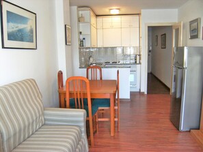 A compact living space with a kitchenette, a dining area with a table and chairs, and a striped sofa.
