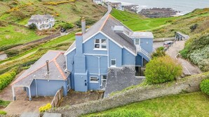 A coastal house with a steep roof, a stone pathway, and a view of the sea.