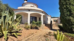 A white villa with a tiled roof, a covered patio, and a stone staircase leading to the entrance. - Villa Castell - Urb Mas Pere (Calonge)