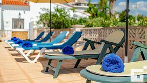 A poolside area with lounge chairs, a table, and an umbrella. - Benicolada - Grupo Turis - Calpe, Costa Blanca (Calpe)