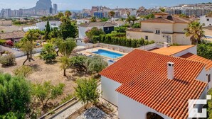 A residential area with a swimming pool, terracotta-tiled roofs, and a view of a cityscape with a prominent mountain in the background. - Benicolada - Grupo Turis - Calpe, Costa Blanca (Calpe)